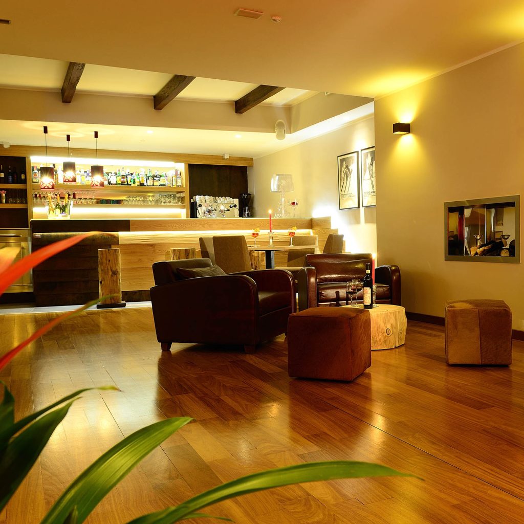 bar dell'hotel con bancone, poltrone e pavimento in legno