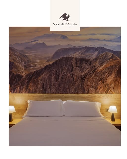 letto matrimoniale sotto un grande quadro di montagne al tramonto